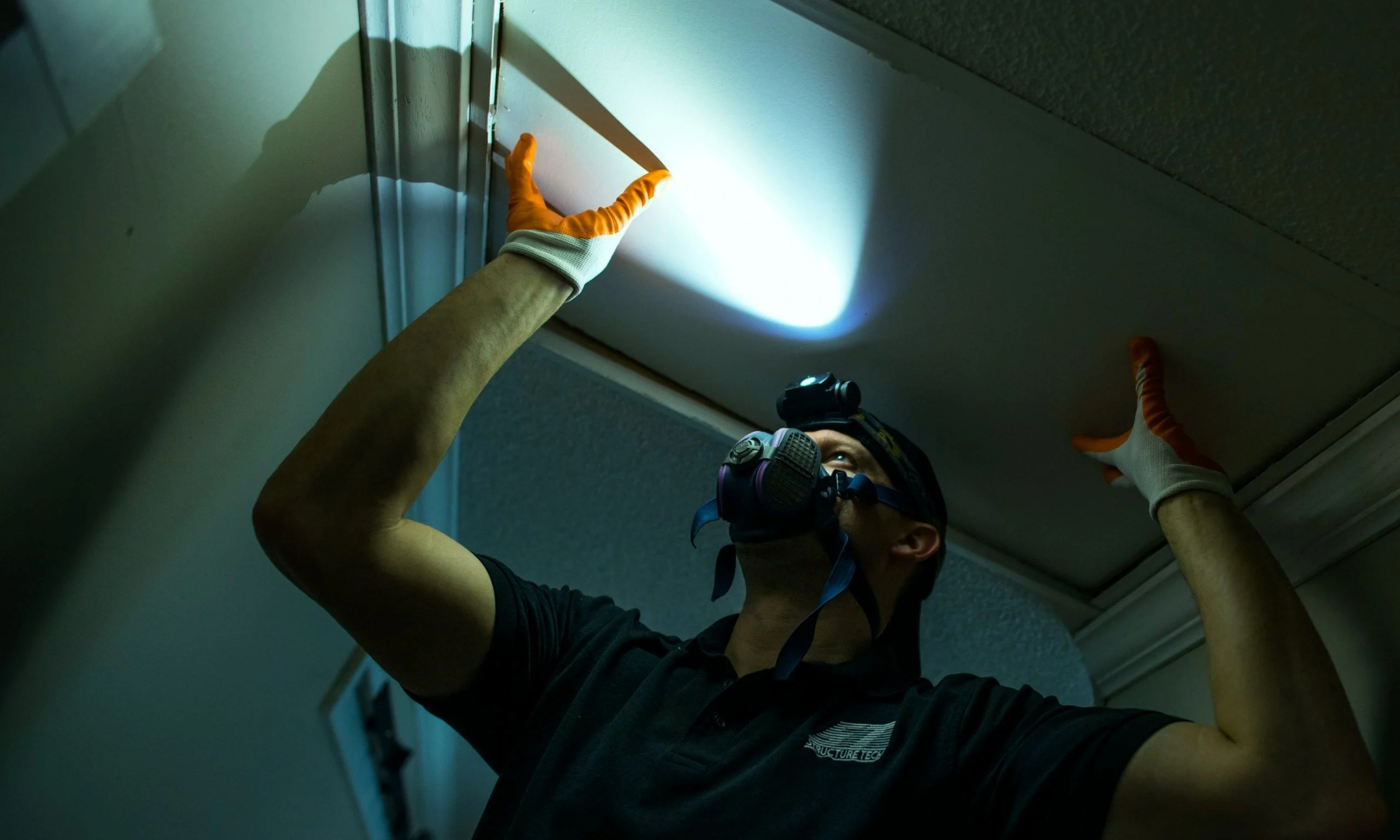 Mold Safe Solutions inspector in a respirator inspecting a water-stained ceiling in a San Diego County home