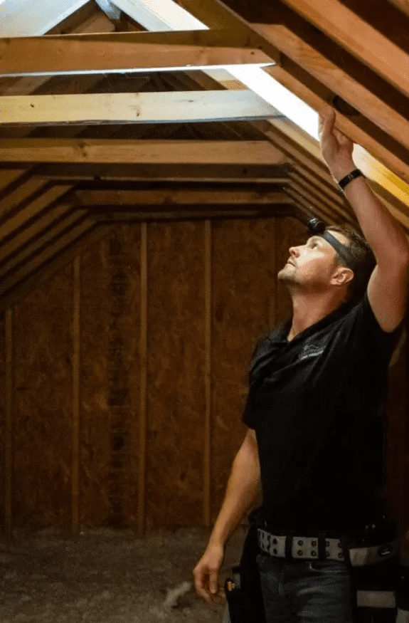 Mold Safe Solutions inspector with a headlamp checking attic framing for mold in a San Diego home